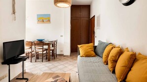 Ett kompakt bostadsutrymme med en soffa, ett tv-appar, ett matbord, stolar och en garderob.