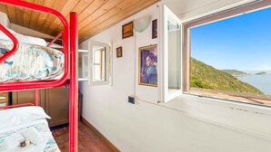 Une chambre avec un lit superposé, un plafond en bois, une fenêtre offrant une vue panoramique et une porte donnant sur une autre pièce.
