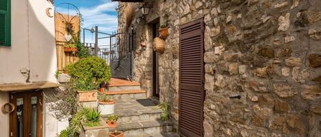 A narrow stone staircase leading to a door with a wooden door and green shutters.