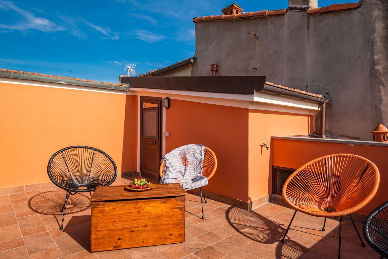 Une terrasse sur le toit avec une table en bois, deux chaises en osier et un petit meuble en bois.
