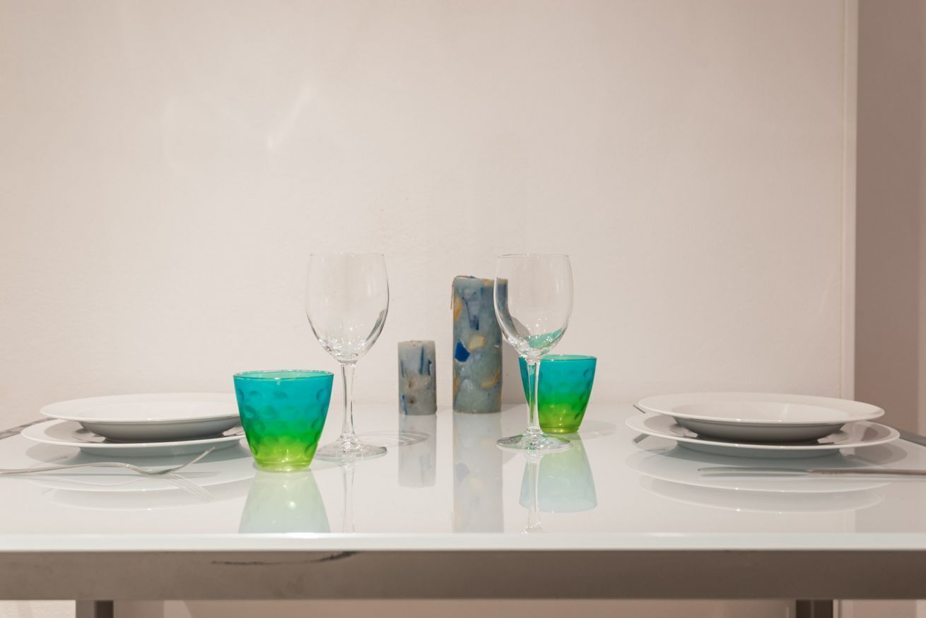 Une table dressée avec deux assiettes, deux verres et une bougie.