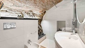 A modern bathroom with a brick wall, a white sink, and a bathtub. - Tin Box, TerreMarine (Riomaggiore)