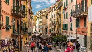 A narrow street lined with colorful buildings, a small covered area, and people walking. - Tin Box, TerreMarine (Riomaggiore)