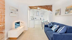 A modern living room with a blue sofa, a white TV stand, and a brick accent wall. - Tin Box, TerreMarine (Riomaggiore)