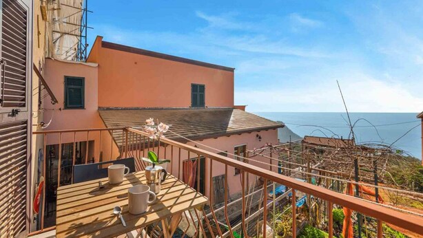 Un balcon avec une table, des chaises et une vue sur la mer.