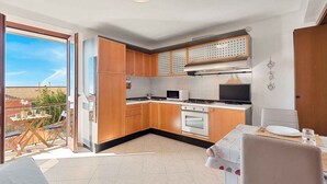 Une cuisine moderne avec des meubles en bois, un four à micro-ondes, une cuisinière et un coin repas comprenant une table et des chaises.