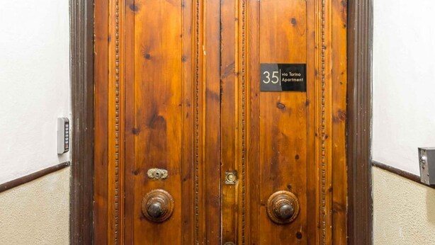 Een houten dubbele deur met een bord waarop staat '35 via Forre Apartment'.