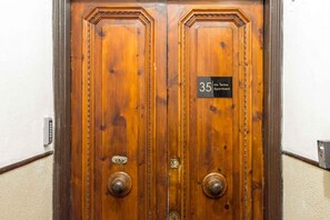 A wooden double door with a sign reading "35 via Forre Apartment."