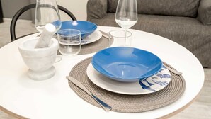 Een eettafel gedekt met blauwe en witte borden, een glas, een wijnglas en een marmeren zout- en peperstel.