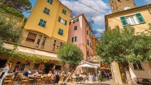 Une rue étroite bordée d’immeubles, avec des terrasses et un beffroi.