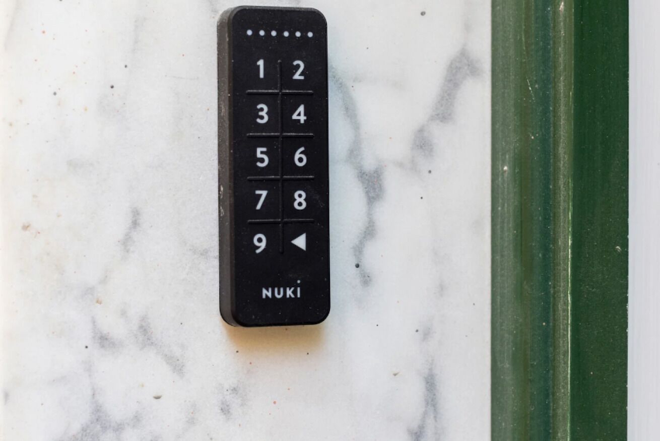 Une télécommande noire dotée d’un pavé numérique et de boutons directionnels, posée sur une surface en marbre.