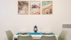 Un coin repas avec une table dressée pour deux personnes, deux chaises, un chemin de table bleu et une lanterne.