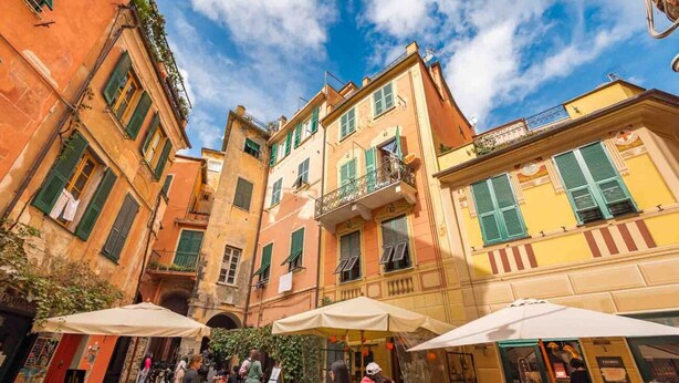 Une rue étroite bordée d’immeubles dotés de balcons et de volets, ce qui évoque un cadre urbain d’époque.