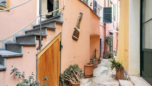 Une ruelle étroite avec une porte en bois, un escalier et des plantes en pot.