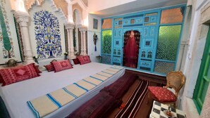 Een klassieke kamer met een groot bed, gedetailleerde wanddecoraties en een vloer met een patroon.
