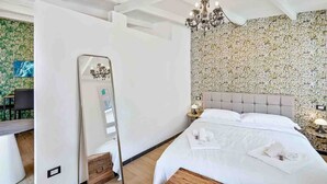 A hotel room with a large bed, a chandelier, a mirror, and a floral wallpaper. - Enchantment, TerreMarine (Riomaggiore)
