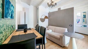 A modern living room with a wooden dining table, black chairs, a beige sofa, and a round coffee table. - Enchantment, TerreMarine (Riomaggiore)