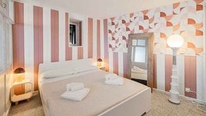 Una camera d'albergo con un letto grande, due comodini con lampade, una finestra e una parete decorata.