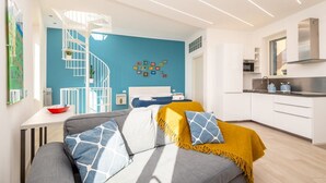 Een modern appartement met een zithoek, inclusief een bank, een gele plaid en een blauwe muur met kindertekeningen.