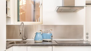 Een moderne keuken met een roestvrijstalen spoelbak, een blauwe waterkoker en een broodrooster op het aanrecht.