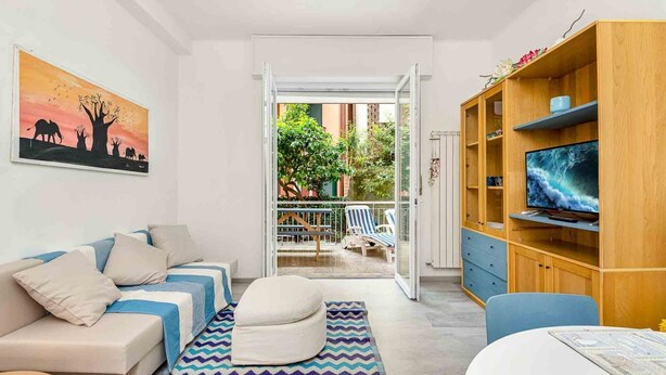 A modern living room with a sofa, ottoman, and a TV on a wooden cabinet. - Corner 89, TerreMarine (Monterosso al Mare)