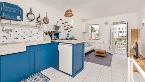 Une cuisine de taille réduite avec des meubles bleus, un réfrigérateur blanc et un dosseret carrelé.