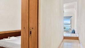 A hotel room with a bed, a wooden door, and a view of the sea through an open balcony. - Neverland, Terre Marine (Portovenere)