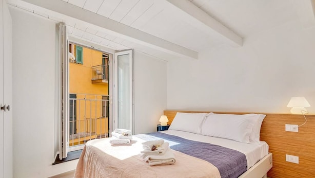 A bedroom with a bed, a nightstand, a lamp, and a view of a balcony. - Via del Mare, Terre Marine (Riomaggiore)