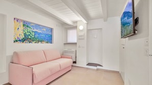 A modern living room with a pink sofa, a large painting, a flat-screen TV, and a white ceiling. - Via del Mare, Terre Marine (Riomaggiore)