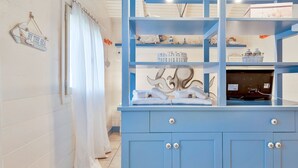A bathroom with a blue vanity, white towels, and a decorative wall sign. - The Chalet by the Sea, Terre Marine (Vernazza)