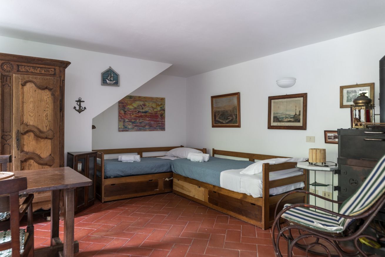 Une pièce comprenant deux lits en bois, une table en bois, une chaise et un buffet.