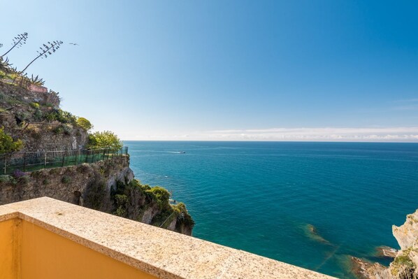 A coastal view with a clear sky, a rocky cliff, and the sea.