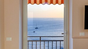 Een deur die uitkomt op een balkon met uitzicht op zee en boten.