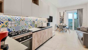 A modern kitchen with a tiled backsplash, a gas stove, and a dining area with a table and chairs. - La Frida, Marine Lands (Lerici)