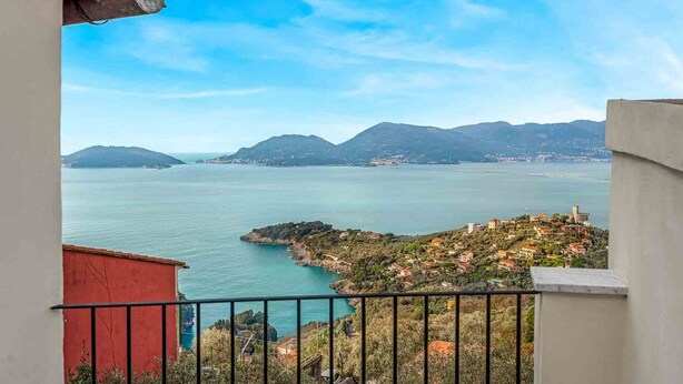 A coastal view from a balcony with a clear sky, a calm sea, and distant mountains. - La Frida, Marine Lands (Lerici)