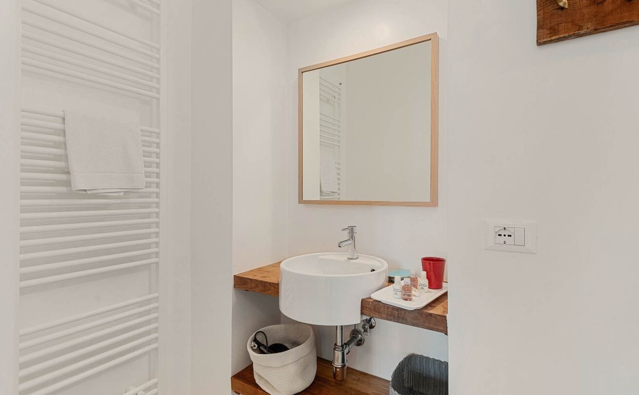 A bathroom with a white sink, wooden countertop, and a mirror.