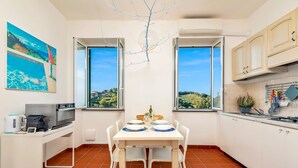 A compact kitchen with a dining area, large windows, and a view of the countryside.