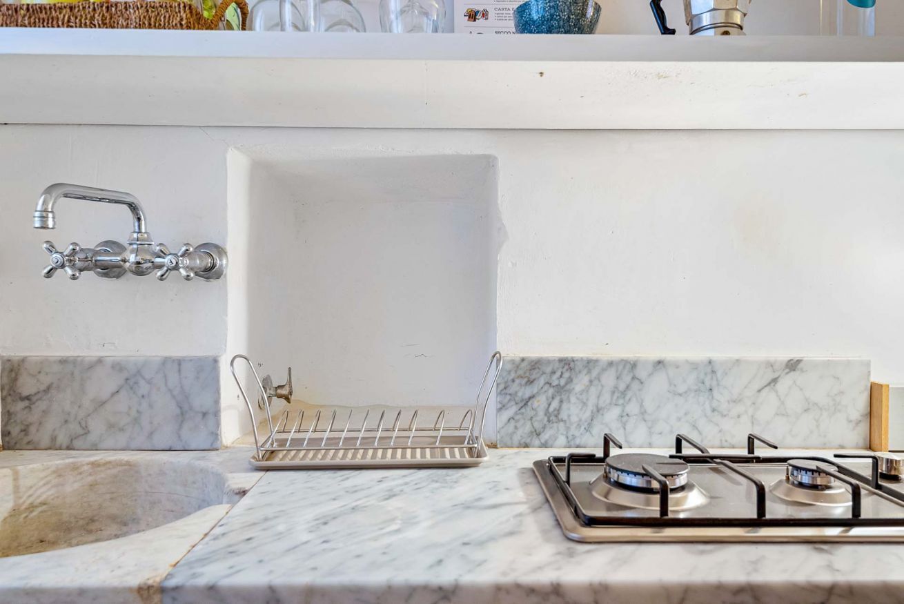 Una cocina con pileta, grifo y estufa a gas.