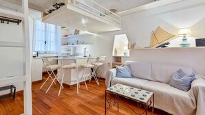 A compact living space with a kitchenette, a dining area with chairs, a sofa, and a coffee table.