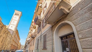 Una calle estrecha con edificios históricos, una destacada torre del reloj y una entrada porticada.