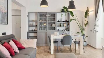 Un soggiorno moderno con un divano grigio, un tavolo da pranzo con sedie e un mobile contenitore grigio incassato con ante in vetro.