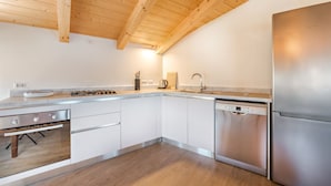 A modern kitchen with wooden beams, stainless steel appliances, and white cabinetry. - Viewpoints, nature, walks and sea (Lerici)