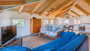 A spacious living area with a high wooden ceiling, a sofa, a TV, and a wooden cabinet. - Viewpoints, nature, walks and sea (Lerici)