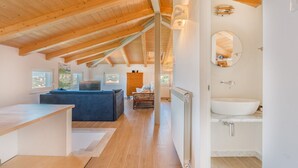 A modern interior with a wooden ceiling, a large window, a blue sofa, a white sink, and a mirror. - Viewpoints, nature, walks and sea (Lerici)