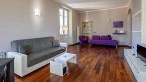 A modern living room with a grey sofa, a purple sofa, and a white coffee table.