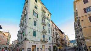 A building with a sign reading "Farmaceutica Spezzina" on the ground floor, surrounded by other buildings.