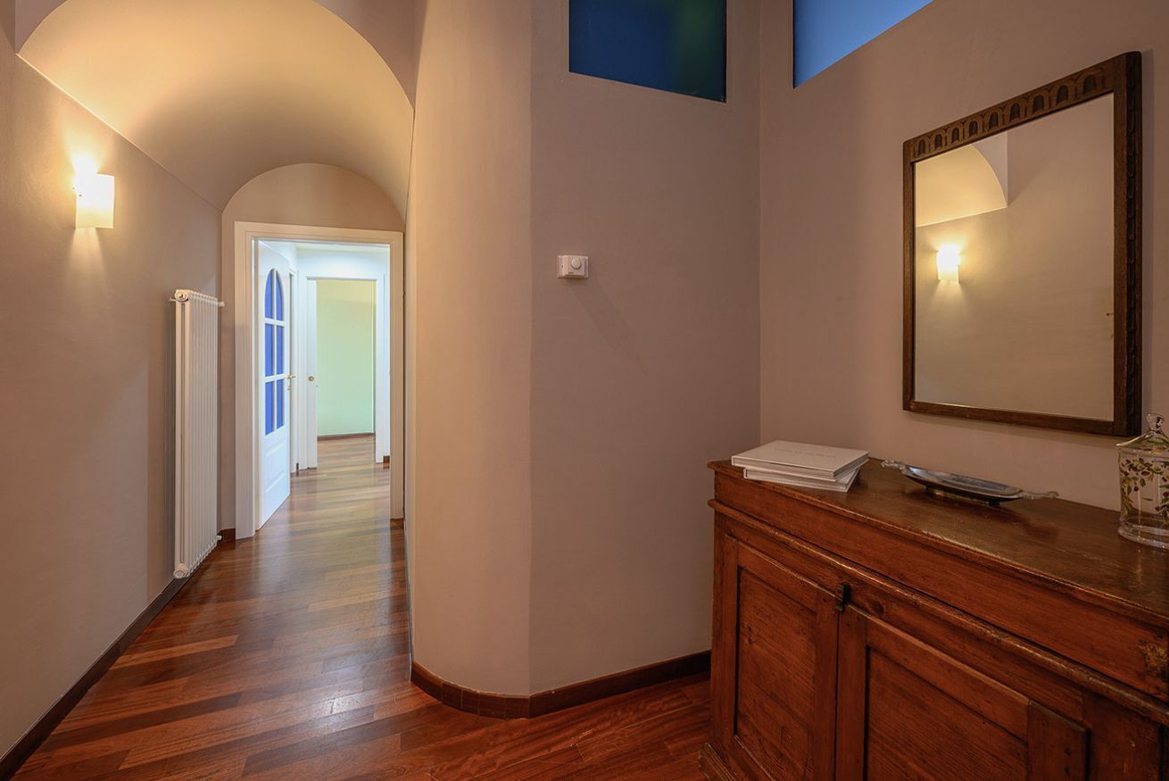 A hallway with wooden flooring, a radiator, and a wooden cabinet with a mirror.