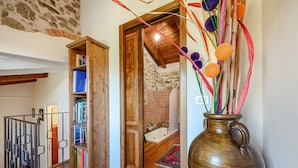 Una estantería de madera, un baño con bañera y un florero con detalles decorativos.