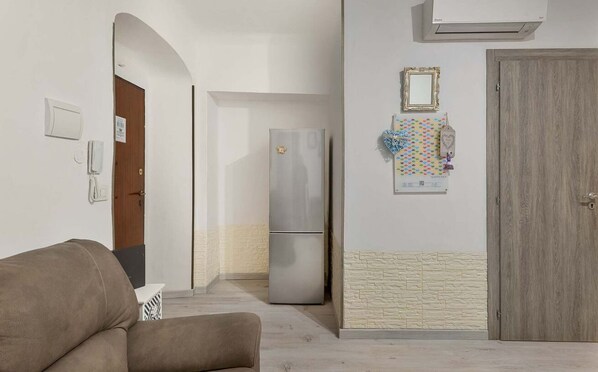 A hallway with a sofa, a refrigerator, a door, and a wall-mounted mirror. - Naples 96, Marine Lands (La Spezia)