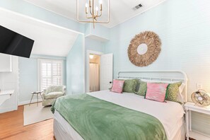 A bedroom with a bed, a chair, a television, and a wall-mounted decorative item.